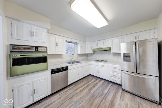 kitchen with light countertops, appliances with stainless steel finishes, white cabinetry, a sink, and under cabinet range hood