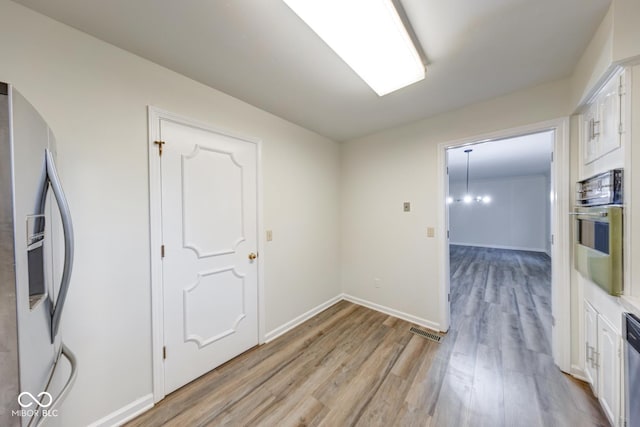 empty room featuring light wood-type flooring, visible vents, and baseboards