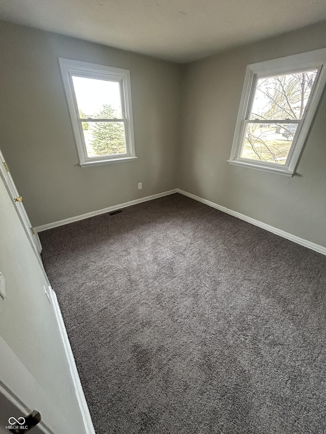 empty room featuring carpet flooring, visible vents, and baseboards