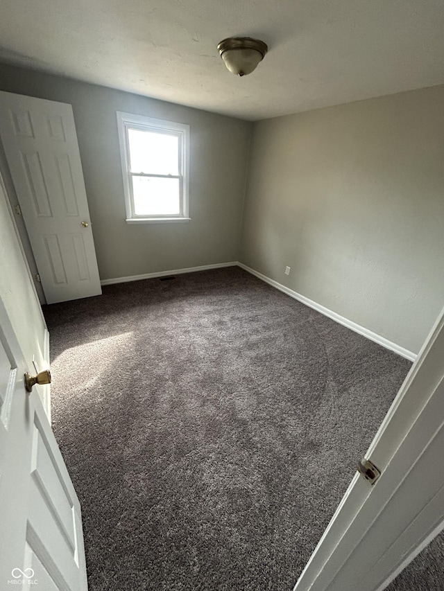 unfurnished bedroom with baseboards and dark colored carpet