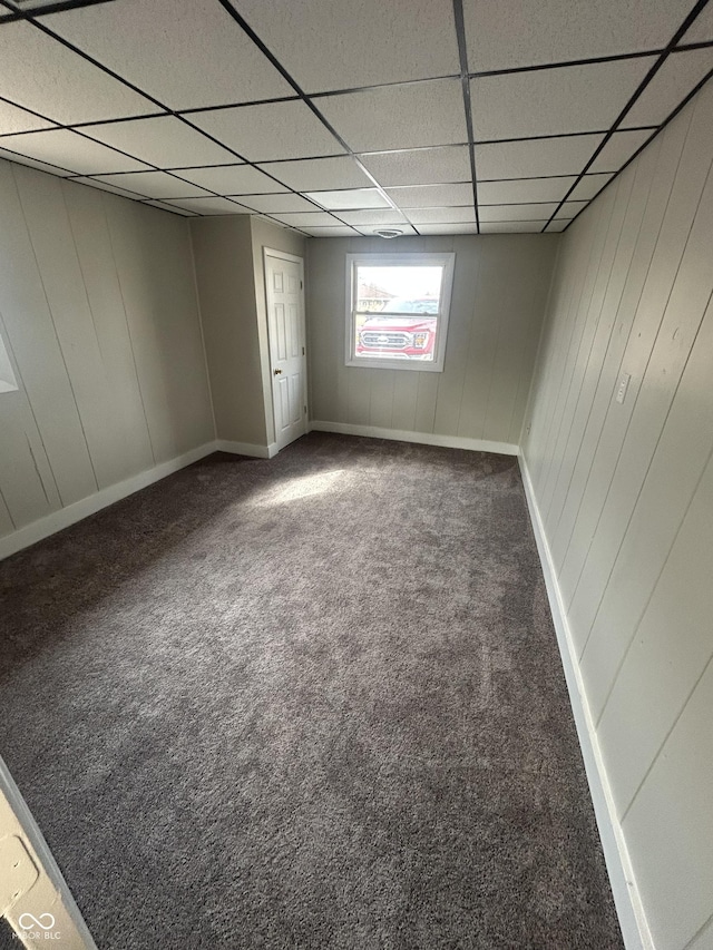 carpeted spare room with a paneled ceiling and baseboards