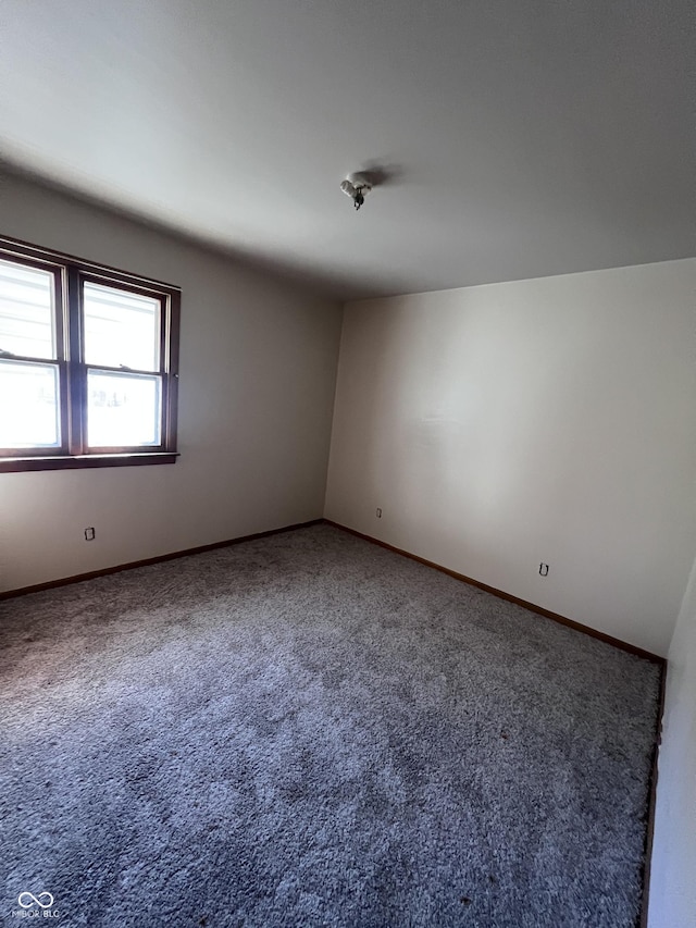 carpeted empty room featuring baseboards