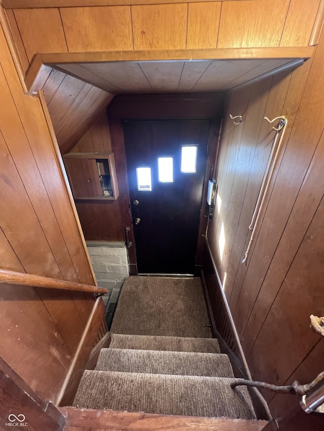 staircase featuring wooden walls and vaulted ceiling