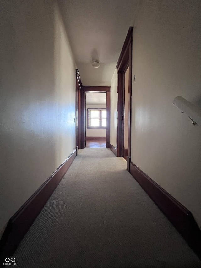 corridor featuring baseboards and light colored carpet