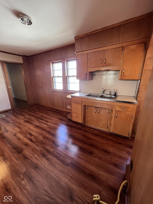 kitchen with visible vents, brown cabinetry, dark wood-style flooring, light countertops, and a sink