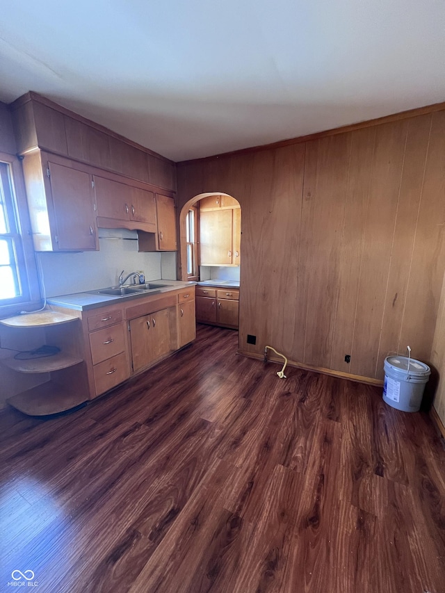 kitchen featuring arched walkways, light countertops, dark wood-style flooring, and a sink