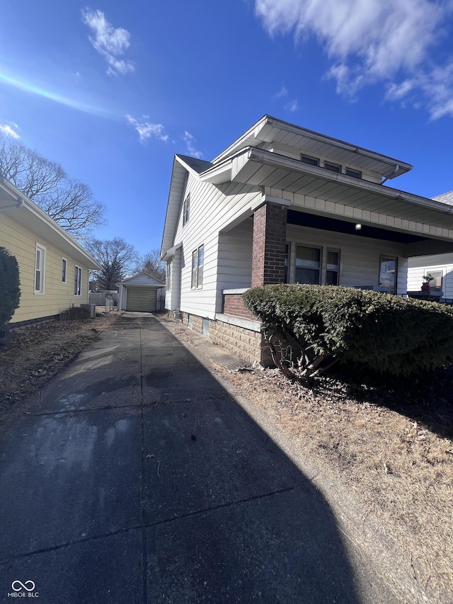 view of home's exterior with a garage, brick siding, and an outdoor structure