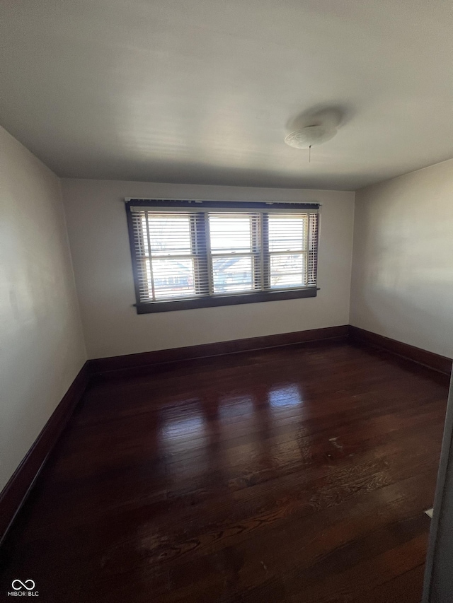 spare room with dark wood-type flooring and baseboards