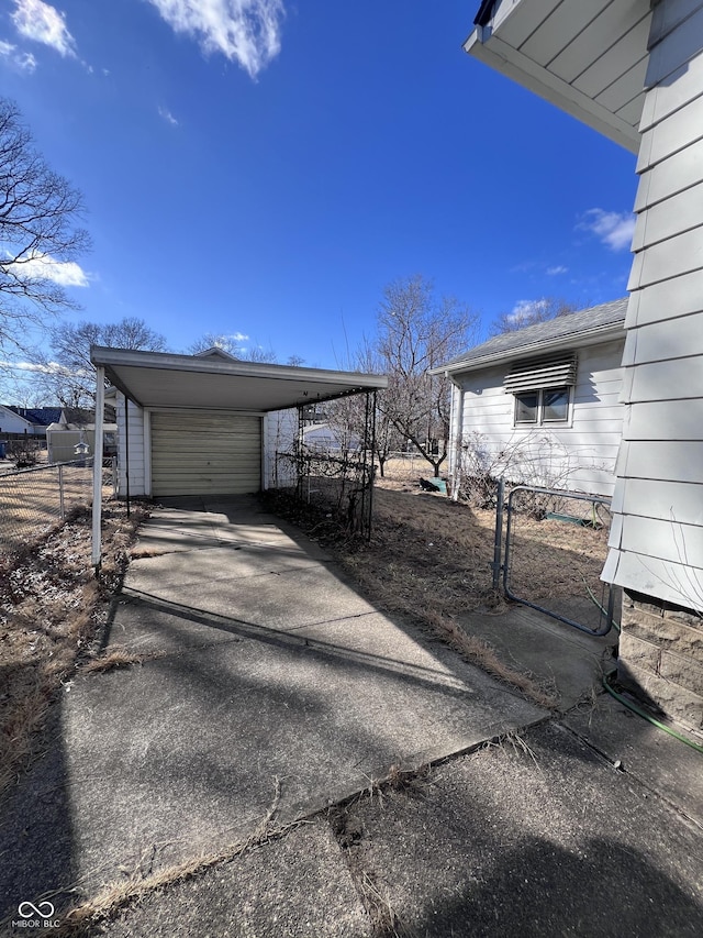 garage with a garage, concrete driveway, and fence