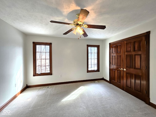 unfurnished bedroom with visible vents, multiple windows, and carpet floors