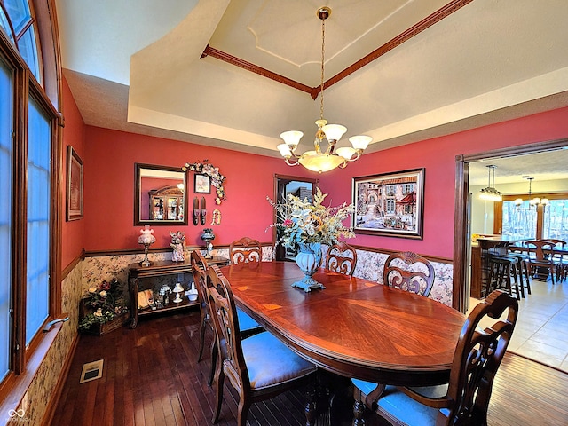 dining room with visible vents, a wainscoted wall, hardwood / wood-style flooring, a raised ceiling, and a notable chandelier