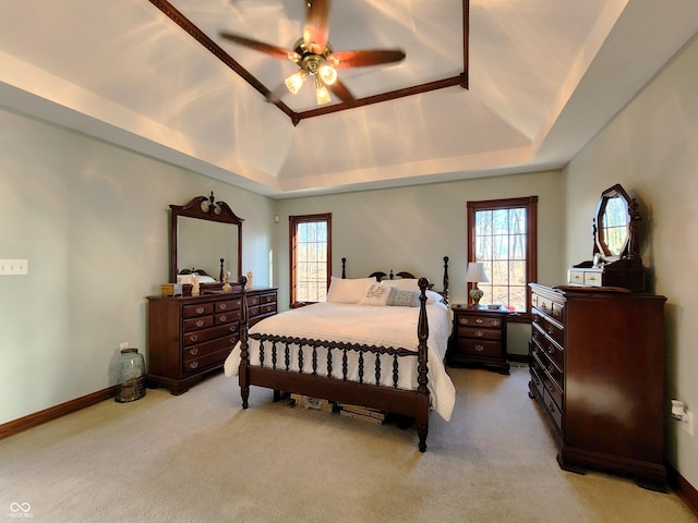 bedroom with a tray ceiling, multiple windows, and light carpet