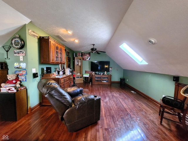 living area with visible vents, lofted ceiling with skylight, a textured ceiling, dark wood finished floors, and baseboards