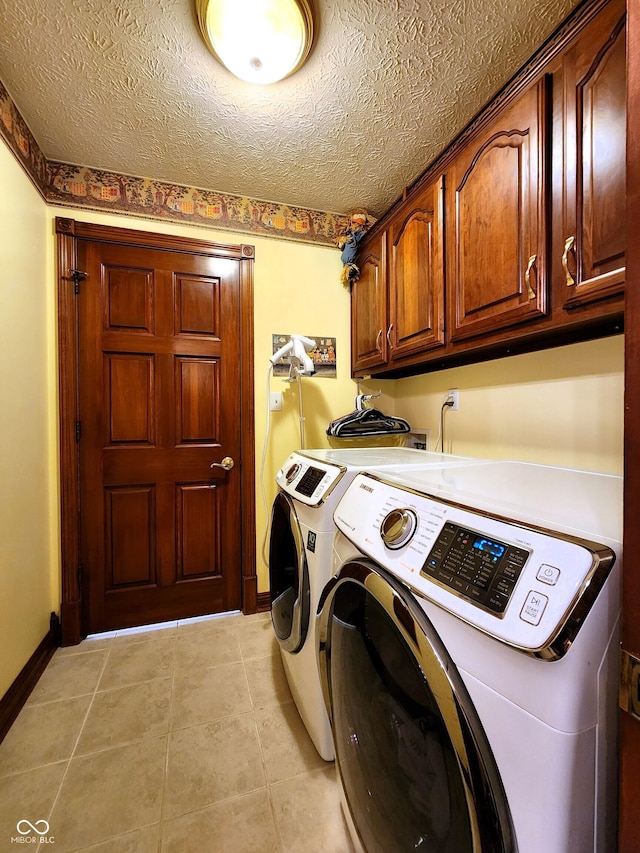 laundry area featuring a textured ceiling, cabinet space, separate washer and dryer, light tile patterned floors, and baseboards