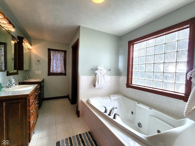 full bathroom featuring a textured ceiling, tile patterned floors, a whirlpool tub, and a sink