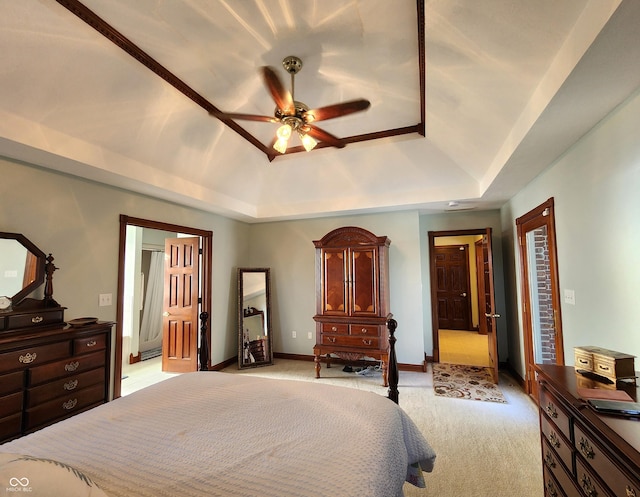 bedroom with a ceiling fan, baseboards, ensuite bath, a raised ceiling, and light colored carpet