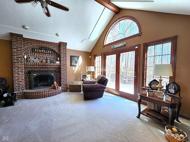 carpeted living room featuring beam ceiling, a brick fireplace, a textured ceiling, and a healthy amount of sunlight