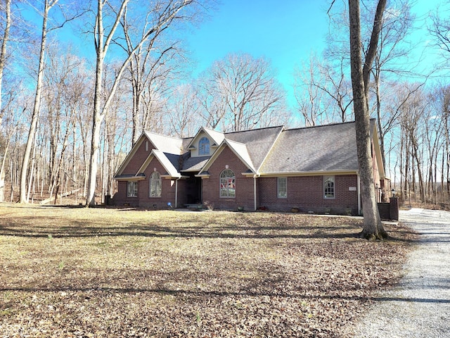 view of front of house featuring driveway, brick siding, crawl space, and a front yard