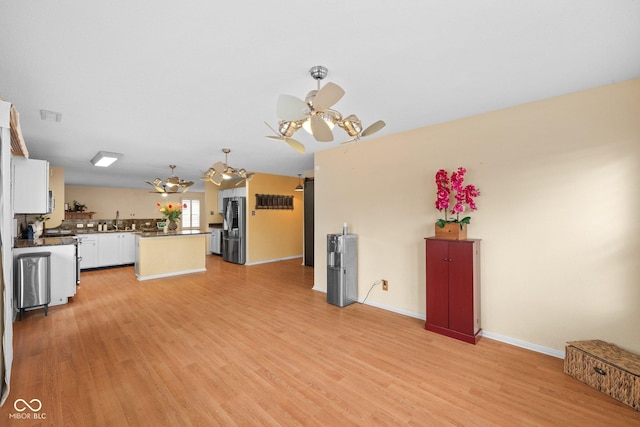 kitchen featuring light wood-style flooring, dark countertops, a center island, white cabinetry, and stainless steel appliances