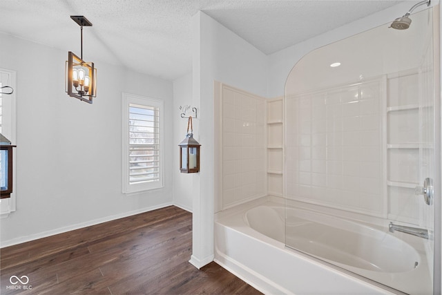 full bathroom featuring baseboards, wood finished floors, tub / shower combination, and a textured ceiling