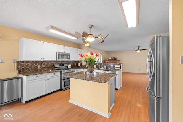 kitchen featuring a kitchen island, white cabinetry, stainless steel appliances, and light wood-type flooring