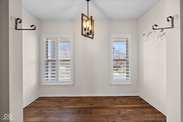 unfurnished dining area with wood finished floors, a healthy amount of sunlight, and baseboards