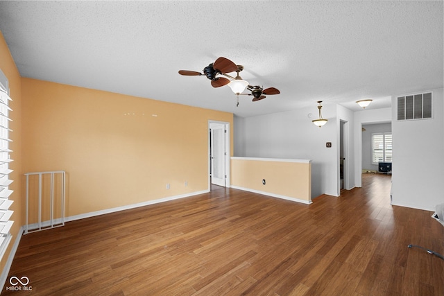 spare room featuring wood finished floors, baseboards, visible vents, ceiling fan, and a textured ceiling