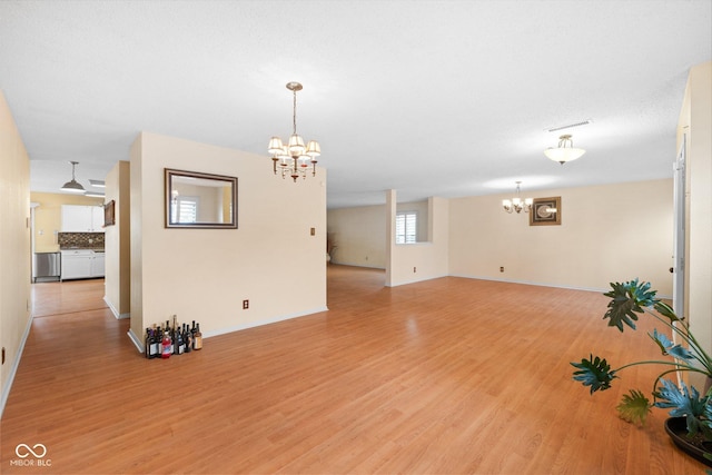 unfurnished living room with visible vents, light wood-style floors, and an inviting chandelier