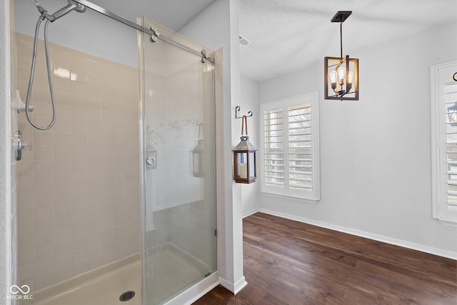 bathroom with a textured ceiling, wood finished floors, a stall shower, and baseboards