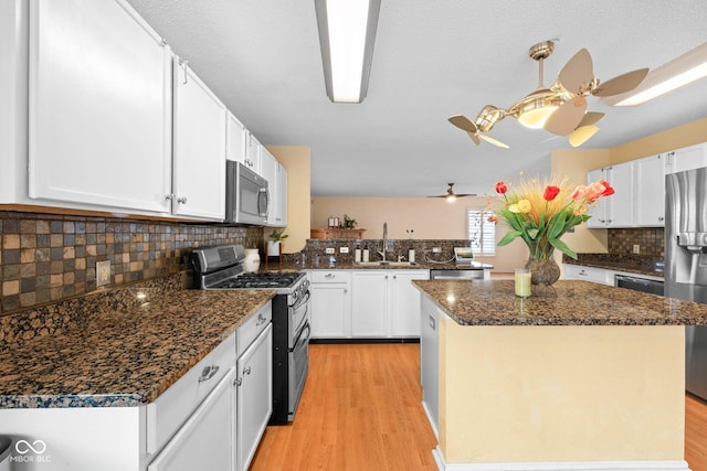 kitchen featuring white cabinetry, stainless steel appliances, light wood-type flooring, and a sink