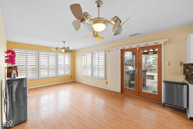 unfurnished living room with light wood-style flooring, radiator heating unit, visible vents, and a textured ceiling