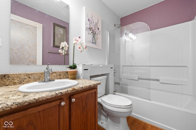 bathroom with toilet, a textured ceiling, shower / washtub combination, wood finished floors, and vanity