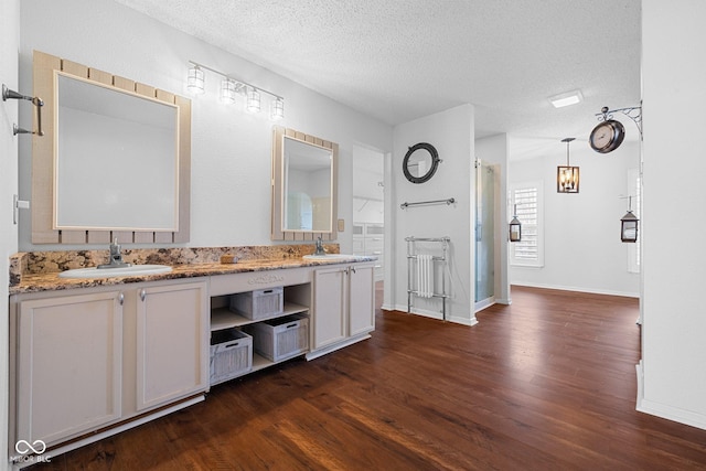 bathroom featuring a textured ceiling, double vanity, wood finished floors, and a sink