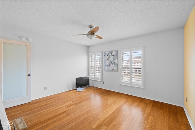 empty room with baseboards, a textured ceiling, ceiling fan, and hardwood / wood-style flooring