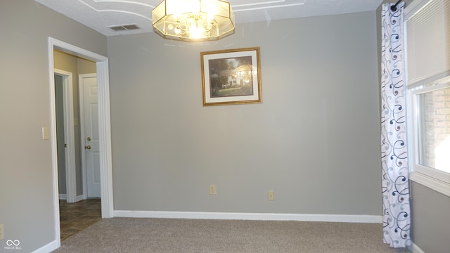 interior space featuring an inviting chandelier, carpet, visible vents, and baseboards