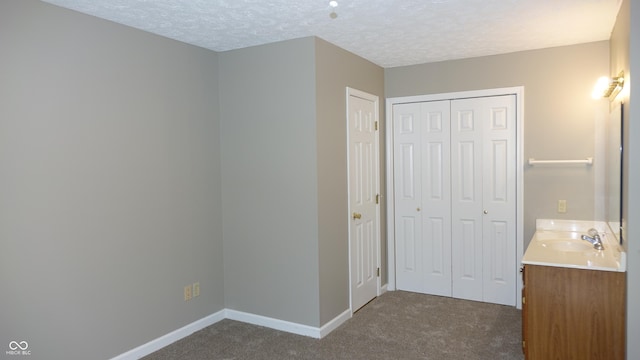 bathroom featuring a textured ceiling, baseboards, and vanity