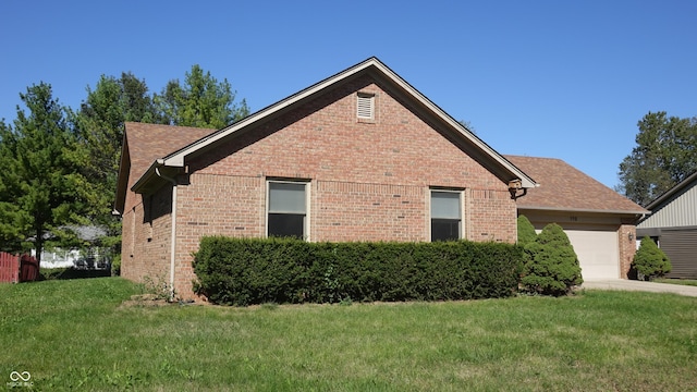 view of property exterior with a garage, brick siding, a lawn, and roof with shingles