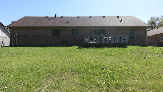 back of house with central air condition unit, brick siding, a shingled roof, a lawn, and a wooden deck