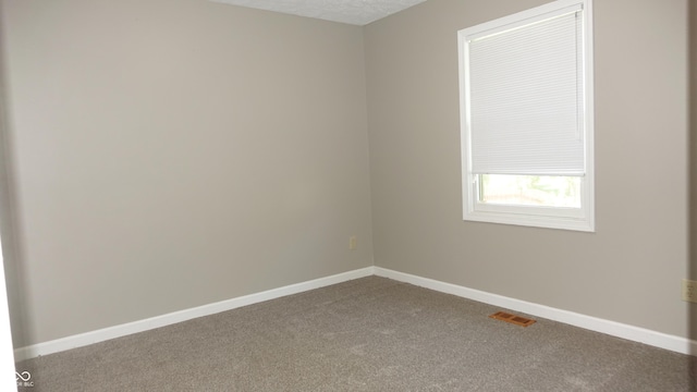 carpeted spare room with visible vents, a textured ceiling, and baseboards