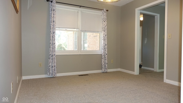 empty room with carpet floors, visible vents, and baseboards