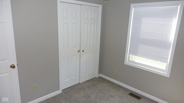 unfurnished bedroom with baseboards, carpet, visible vents, and a closet