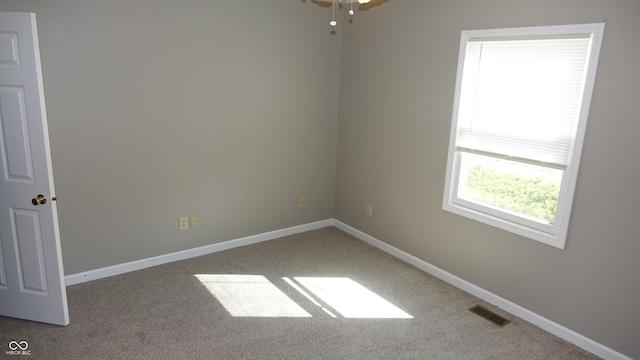 carpeted empty room featuring baseboards and visible vents