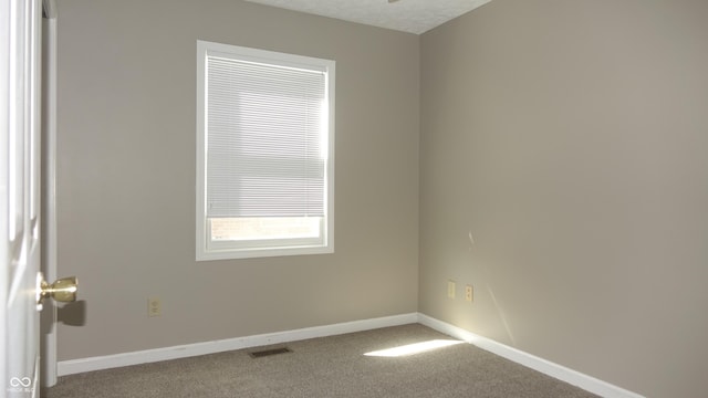 carpeted spare room with visible vents, a textured ceiling, and baseboards