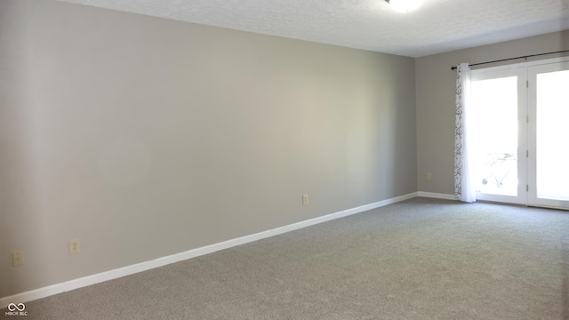 spare room featuring a textured ceiling, baseboards, and carpet flooring