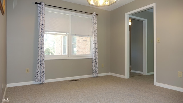 carpeted spare room with visible vents and baseboards