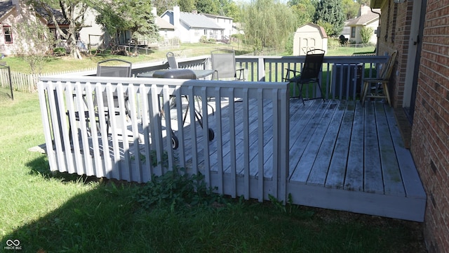 deck with a residential view, a lawn, an outdoor structure, and a shed