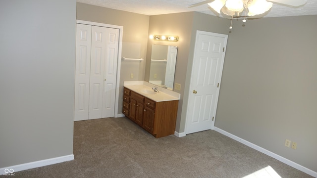 bathroom featuring a closet, carpet, vanity, and baseboards