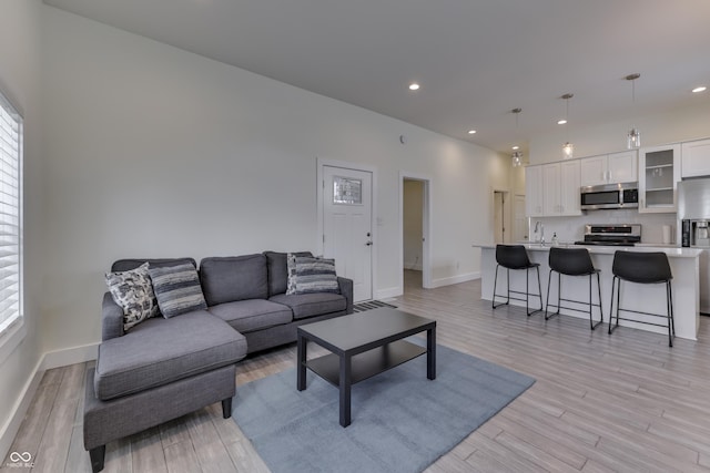 living room featuring light wood-type flooring, baseboards, and recessed lighting