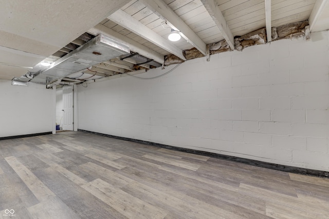 basement with concrete block wall and wood finished floors