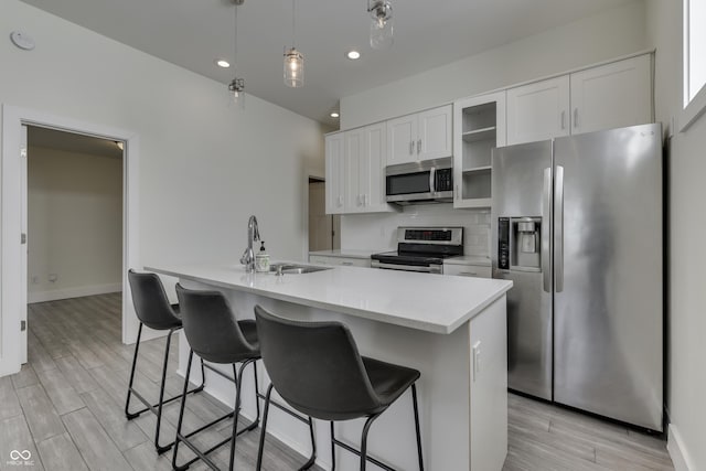 kitchen with light countertops, decorative backsplash, appliances with stainless steel finishes, white cabinets, and a sink